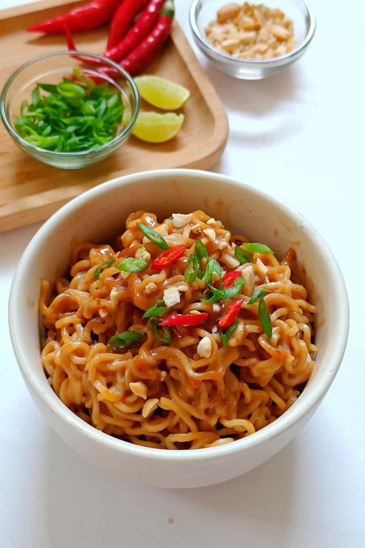 Image showing creamy peanut butter noodles served in a white bowl.