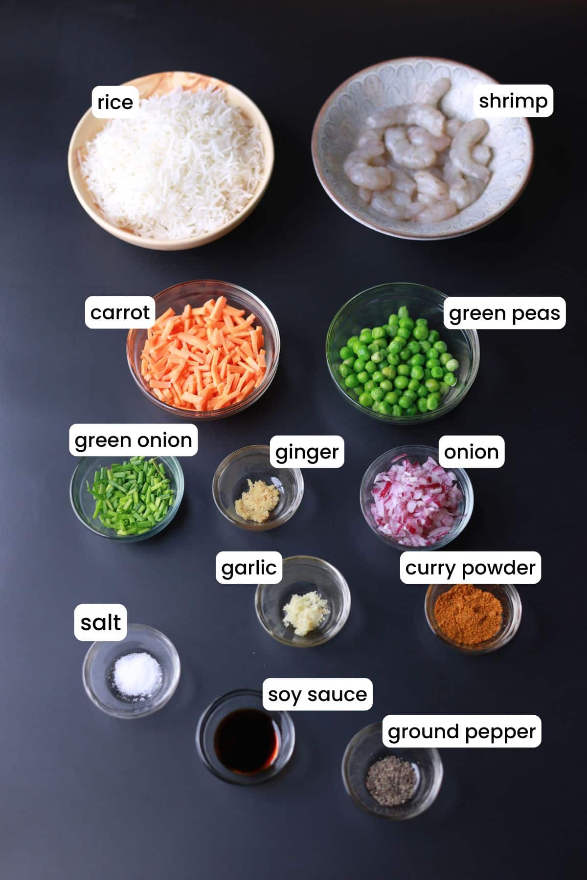 Curry fried rice ingredients are placed on a black background.