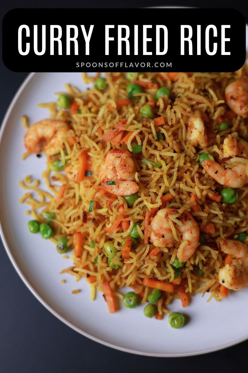 Curry fried rice with shrimp served on a white plate, garnished with green onions and lemon wedge