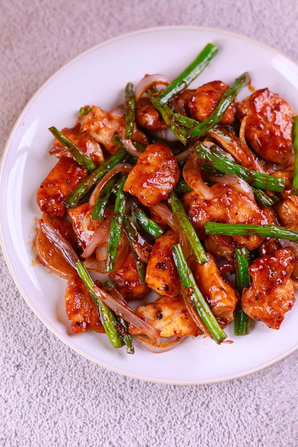 Chicken and green bean stir fry served on a white plate, ready to enjoy.