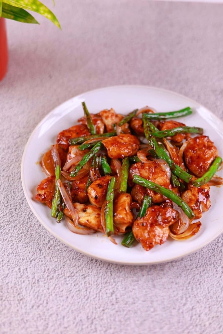 Side angle view of chicken and green bean stir fry served on a plate.
