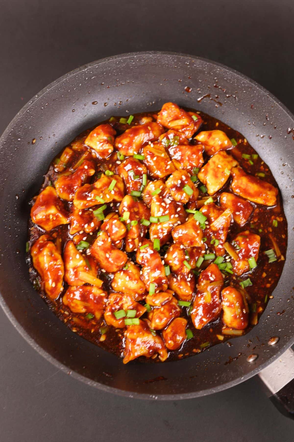 Chinese chicken in a black pan with savory garlic sauce.