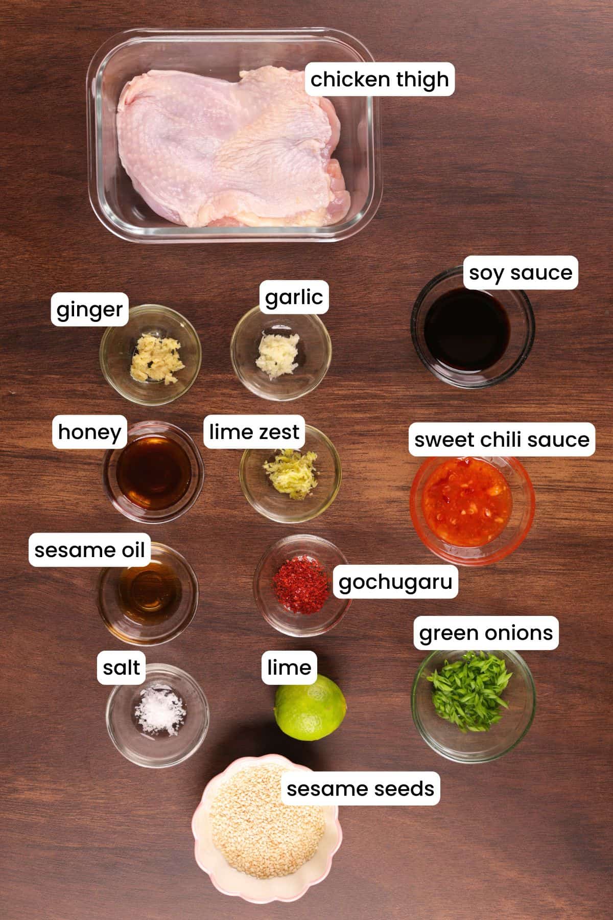 Fresh ingredients for Asian chicken marinade on a wooden background including sesame oil, soy sauce, garlic, and ginger.