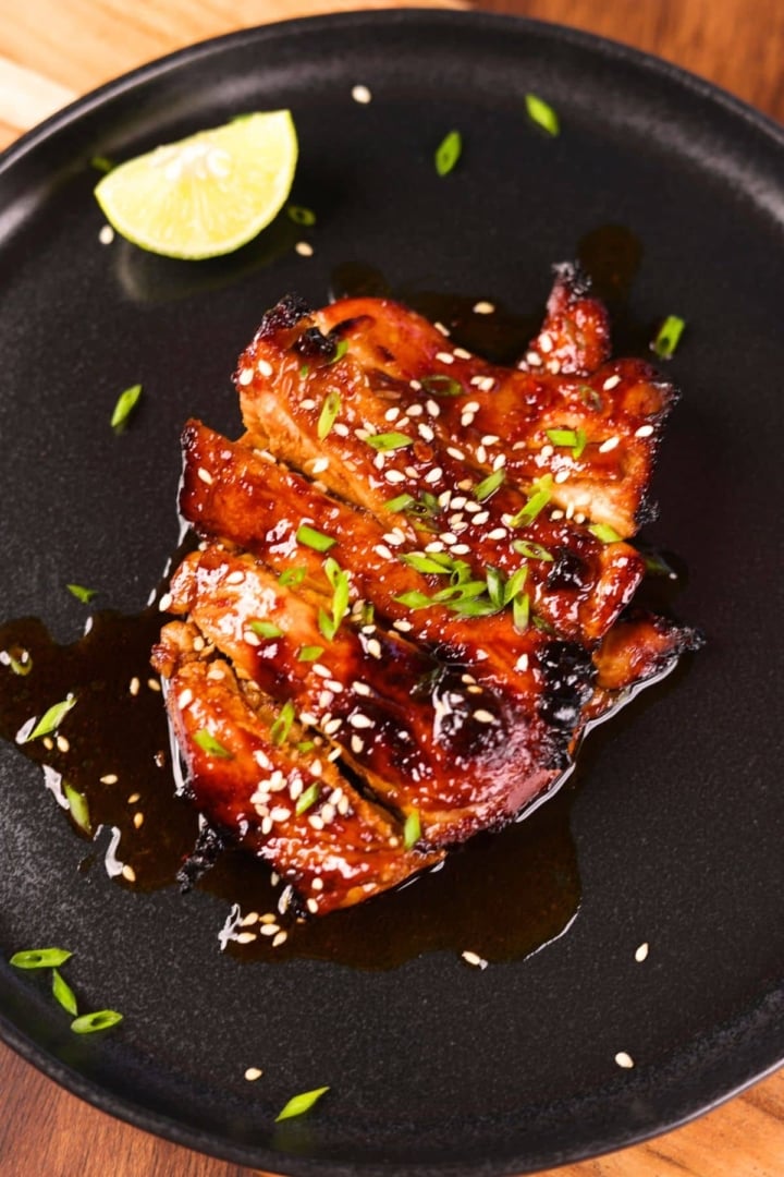 Restaurant-style Asian chicken marinade served on a black plate with garnishing for a flavorful meal.