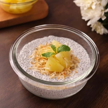 Creamy coconut milk chia seed pudding in a bowl topped with toasted coconut and pineapple.