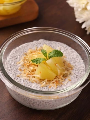 Creamy coconut milk chia seed pudding in a bowl topped with toasted coconut and pineapple.