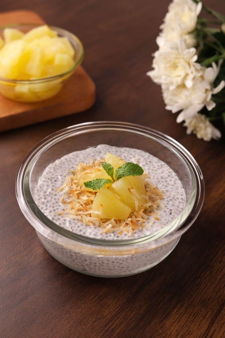 Creamy coconut chia seed pudding topped with toasted coconut and pineapple chunks in a glass bowl.