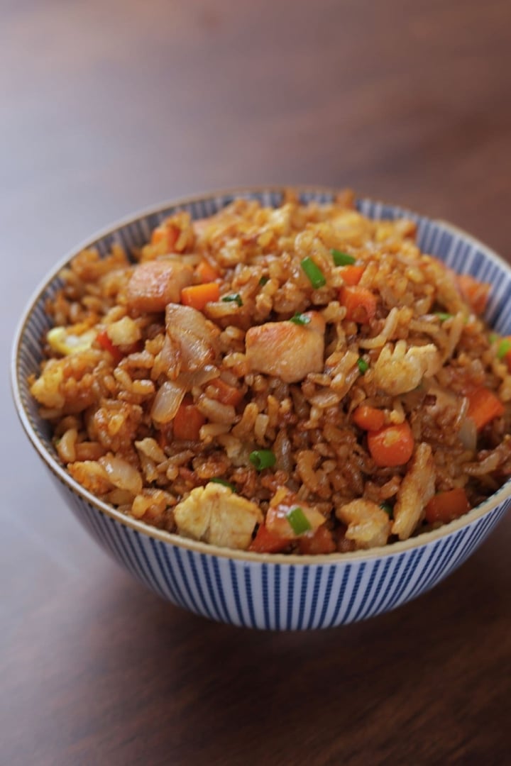 Front view of a bowl of hibachi chicken fried rice topped with green onions, showing fluffy rice and tender chicken pieces.