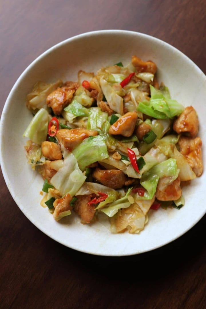 Chicken and cabbage stir fry served in a white bowl.