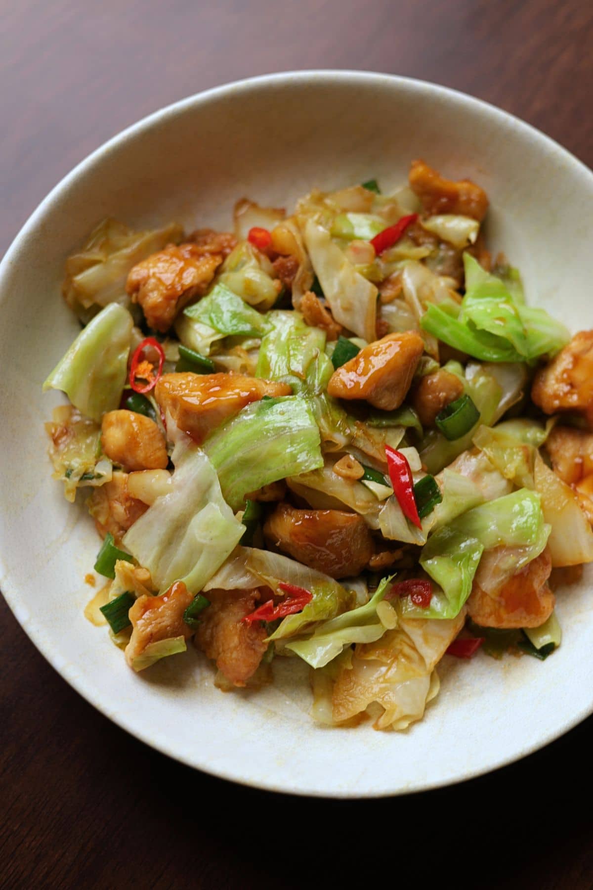 Chinese chicken and cabbage stir fry served in a white bowl.