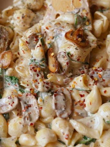 Creamy mushroom and spinach pasta in a off white pan.