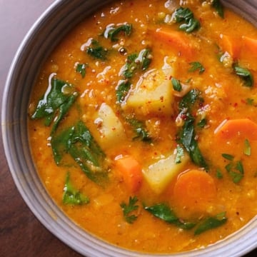 Bowl of Mediterranean lentil and vegetable soup with herbs, showing rich colors and hearty texture.