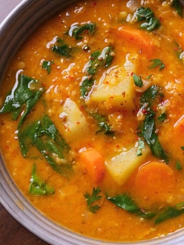Bowl of Mediterranean lentil and vegetable soup with herbs, showing rich colors and hearty texture.
