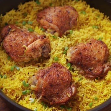 Easy chicken and yellow rice with four chicken thighs in a pan.