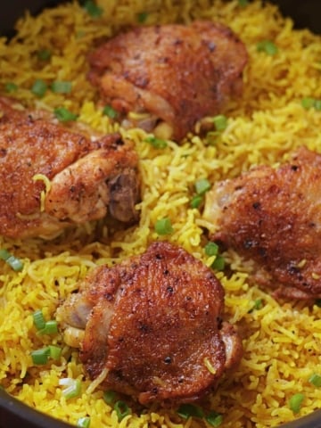 Easy chicken and yellow rice with four chicken thighs in a pan.