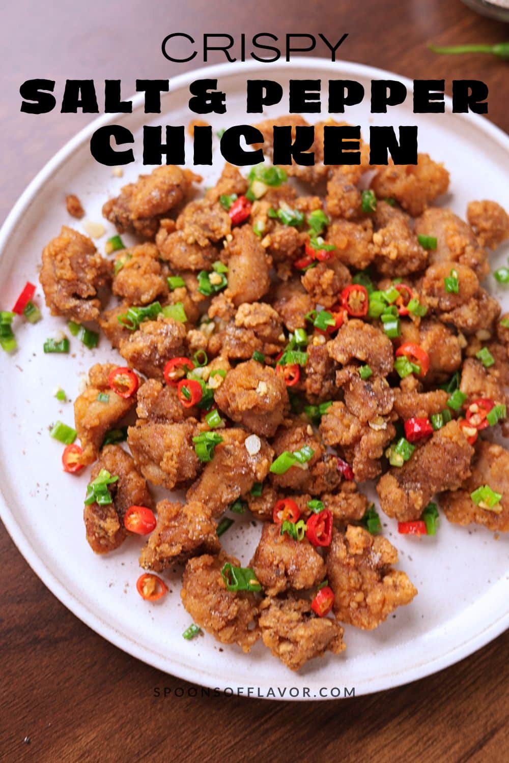 Crispy salt and pepper chicken served on a platter garnished with green onions and red chilies.