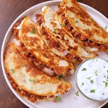 Crispy ground chicken tacos served on a white plate with creamy garlic sauce on the side.