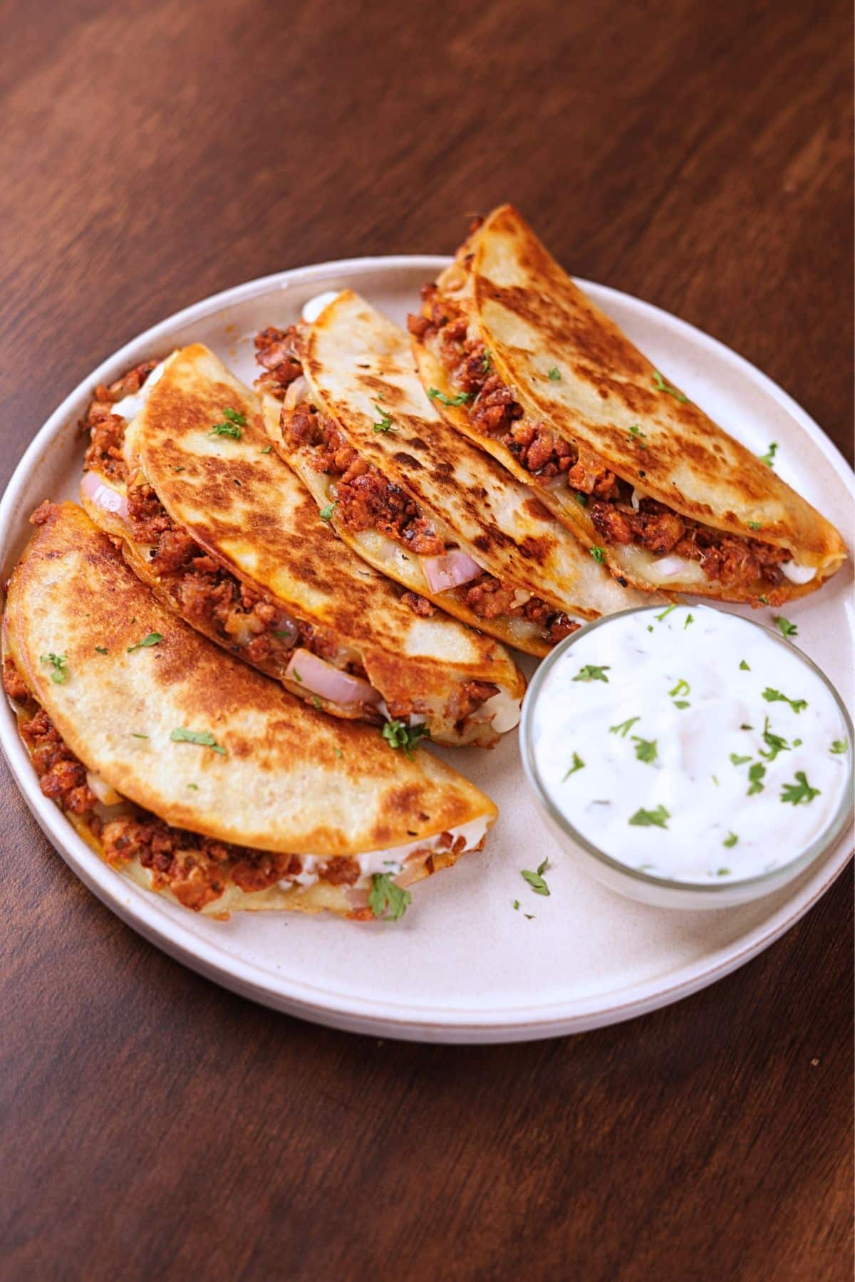 Crispy ground chicken tacos served on a white plate with creamy sauce on the side.