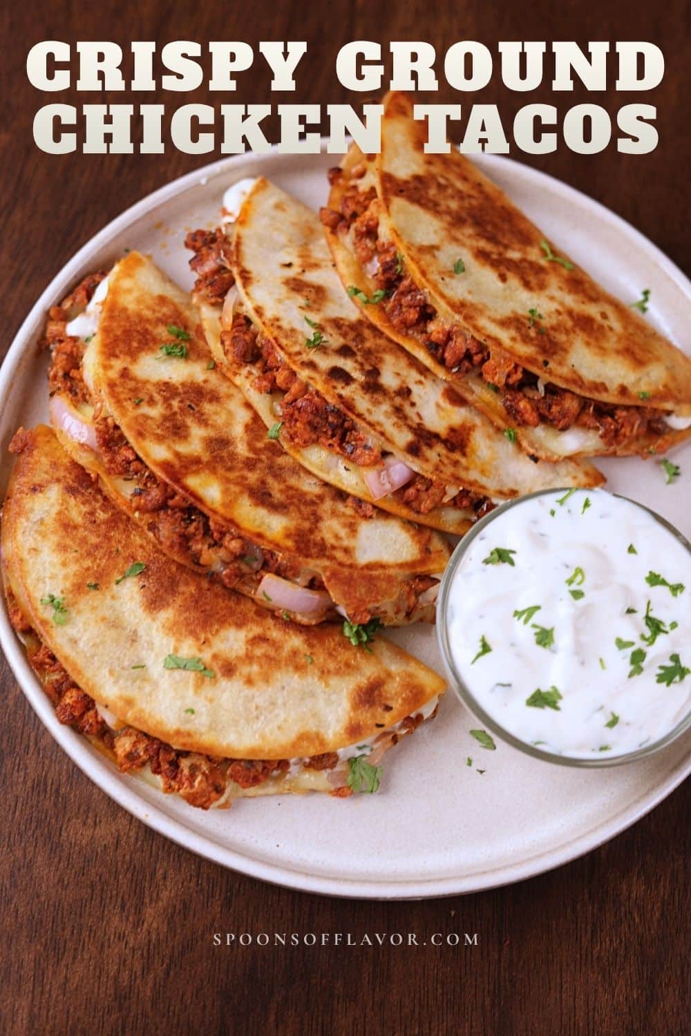 Ground chicken tacos served on a white plate with creamy sauce on the side.