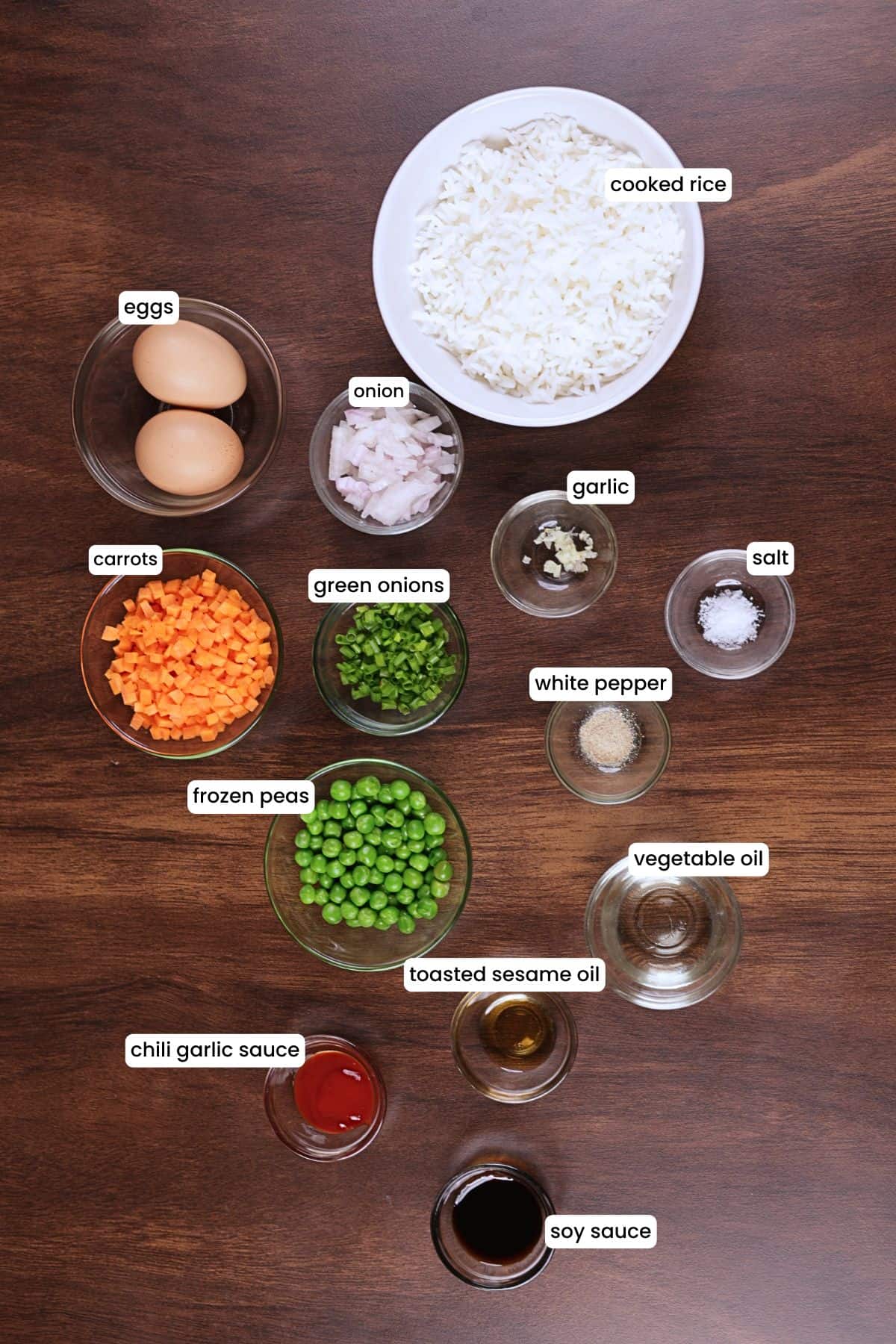 Egg fried rice ingredients including rice, eggs, onion, garlic, carrots, peas, soy sauce, and green onions.