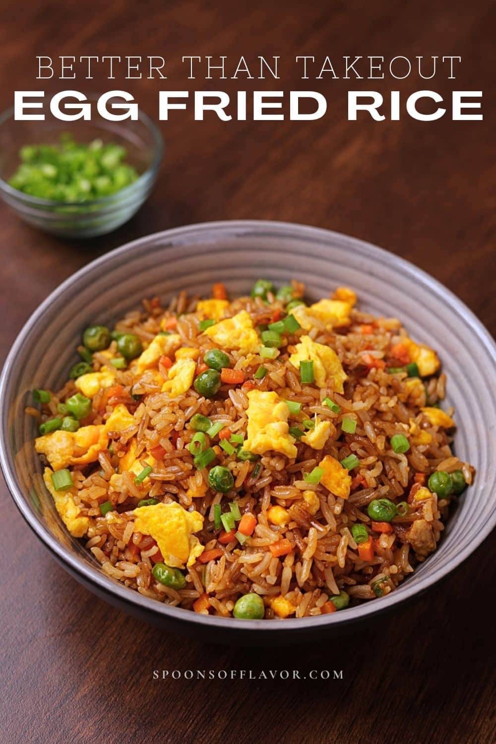 Egg fried rice served in a bowl with carrots, peas, eggs, and green onions.