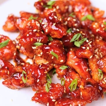 Gochujang chicken garnished with green onions and sesame seeds.