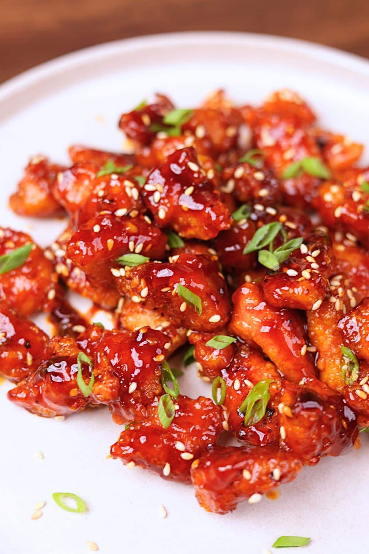 Gochujang chicken garnished with green onions and sesame seeds.