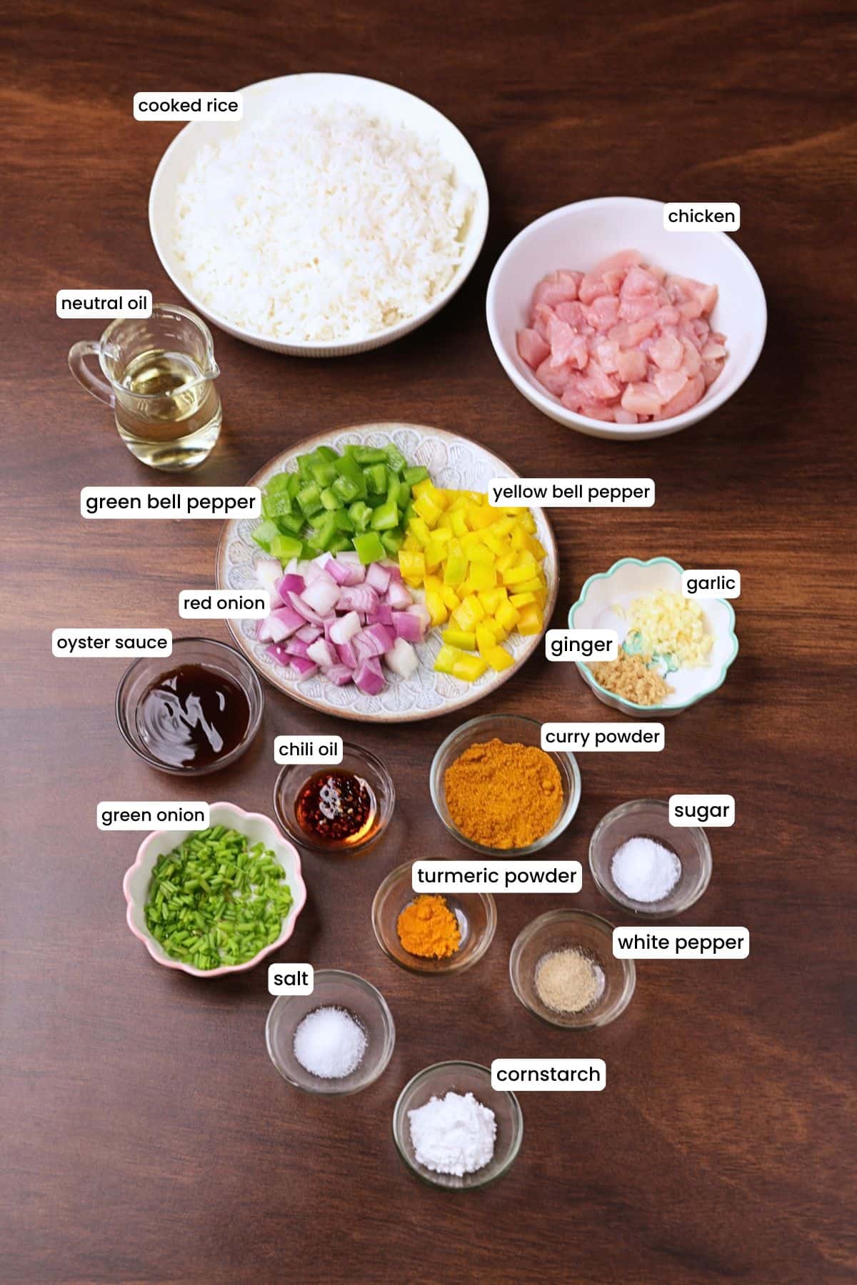 Ingredients for curry chicken fried rice, including chicken, cooked rice, red onion, green and yellow bell peppers, garlic, ginger, curry powder, turmeric, chili oil, and oyster sauce.